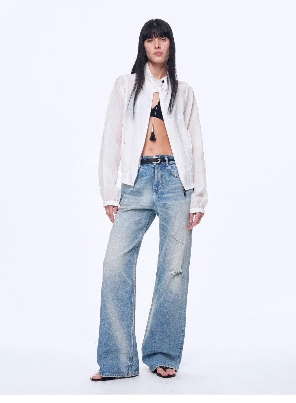 Woman wearing a white shirt, black bra, and light blue jeans on a white background