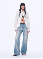 Woman wearing a white shirt, black bra, and light blue jeans on a white background