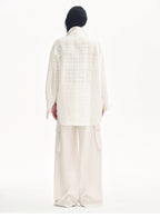 Person wearing a white outfit with a headscarf on a white background
