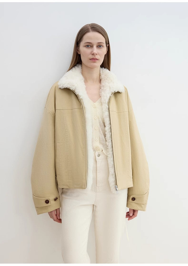 Person wearing a beige coat with white fur lining on a plain background
