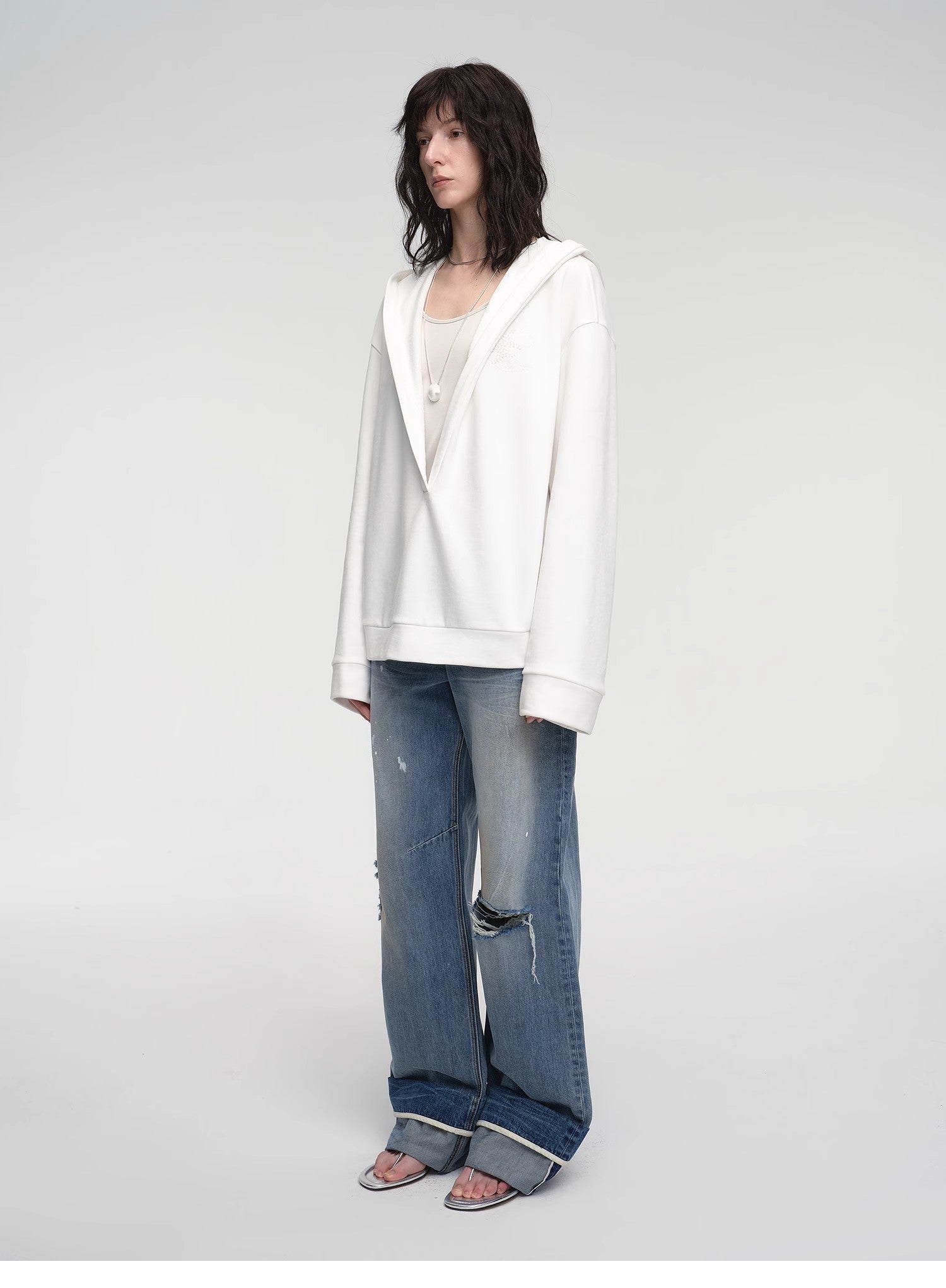 Person wearing a white jacket and blue jeans on a plain background