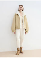Person wearing a beige jacket with white fur lining, white pants, and brown boots against a white background