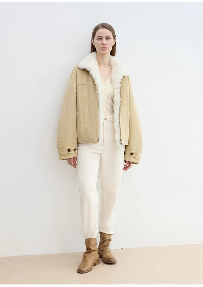 Person wearing a beige jacket with white fur lining, white pants, and brown boots against a white background