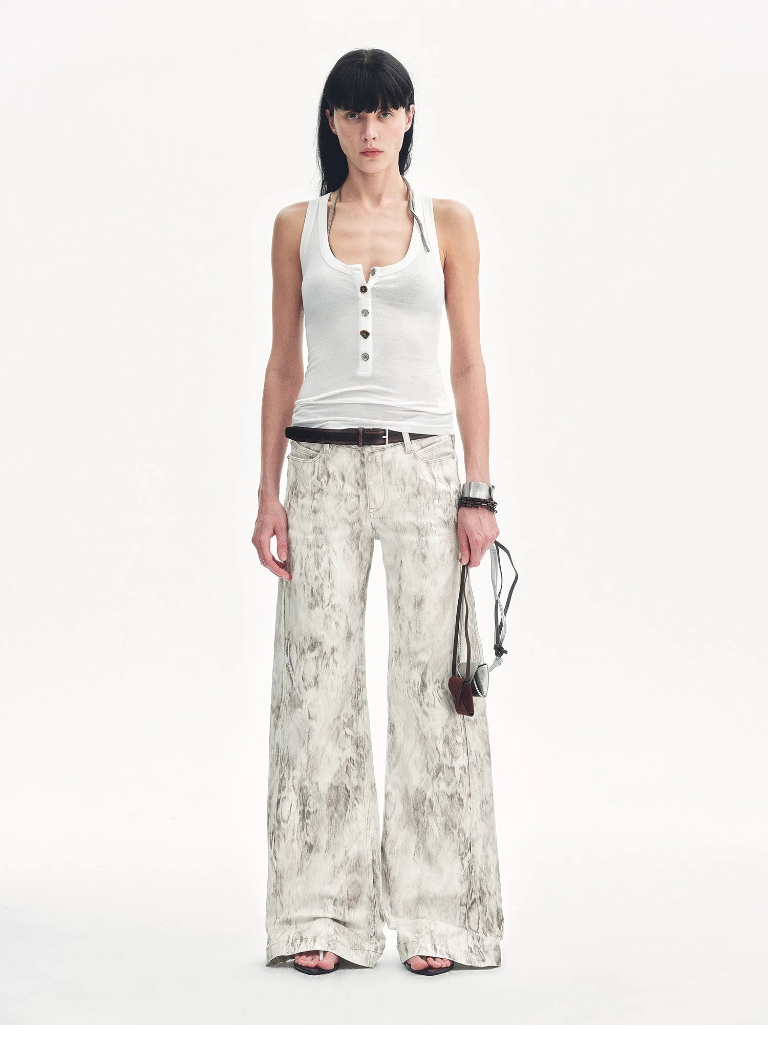 Woman wearing a white sleeveless top and patterned pants on a white background