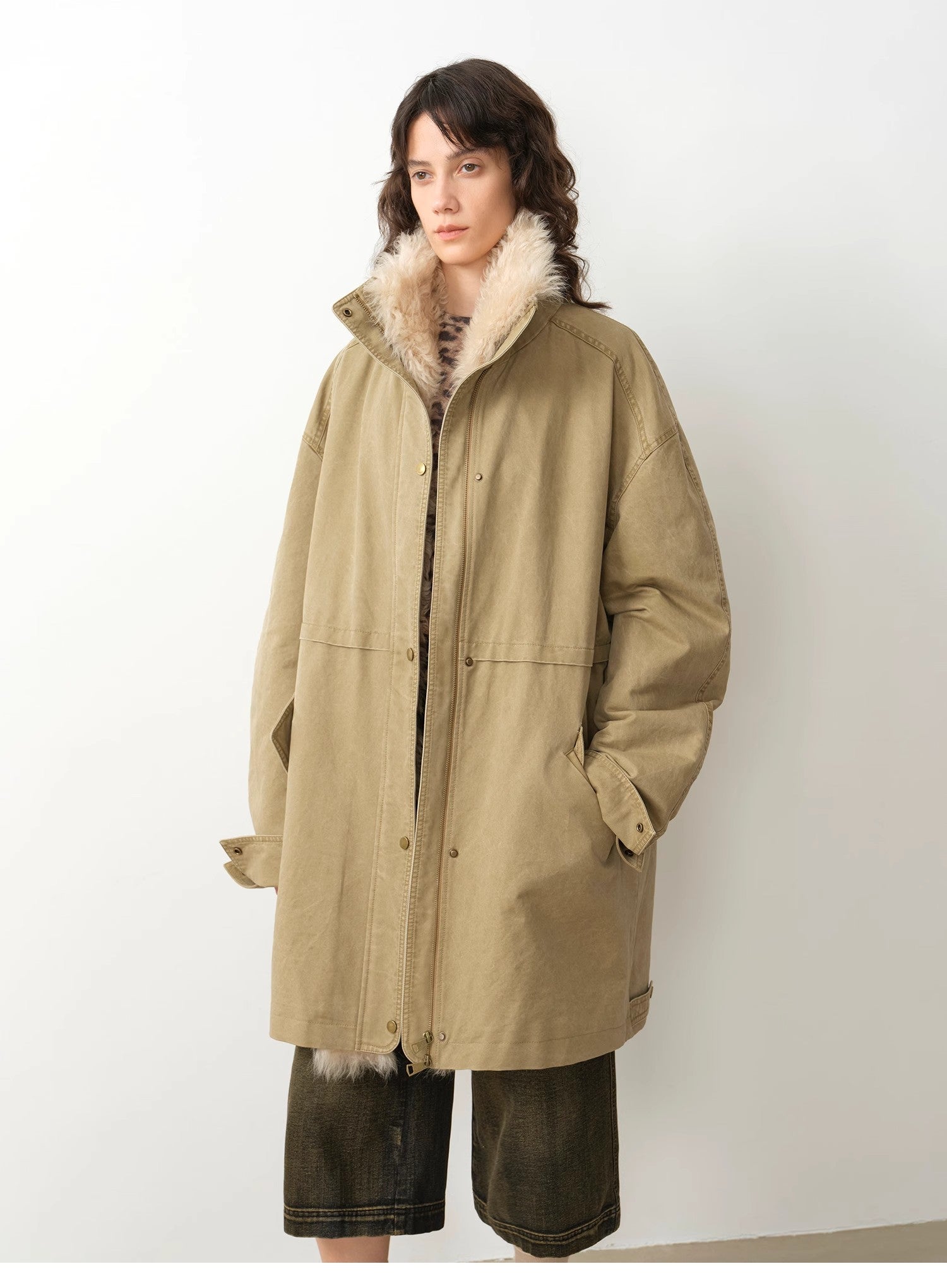 Person wearing a beige coat with fur lining on a white background