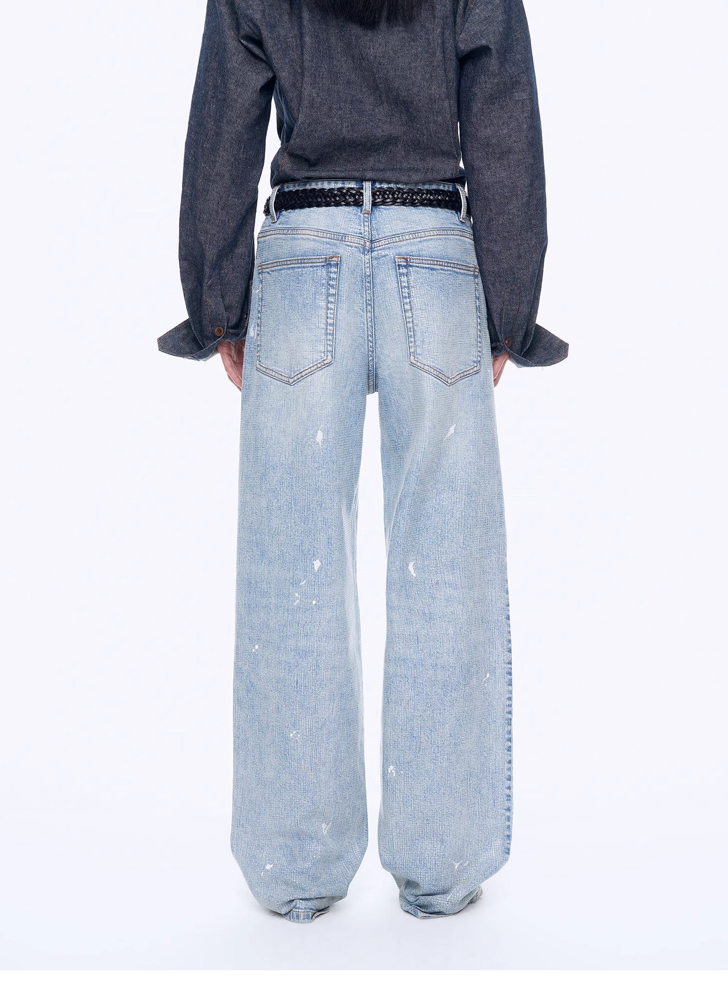 Person wearing light blue jeans and a dark shirt on a white background