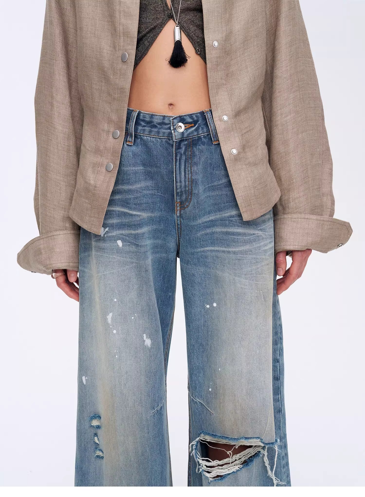 Person wearing a beige shirt and blue jeans on a white background