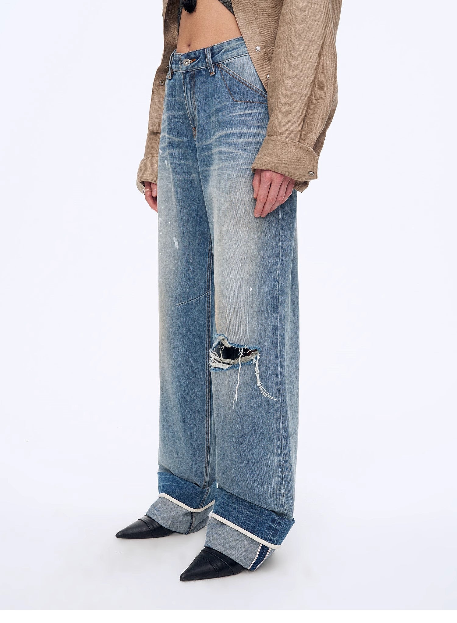 Person wearing a pair of distressed blue jeans on a white background