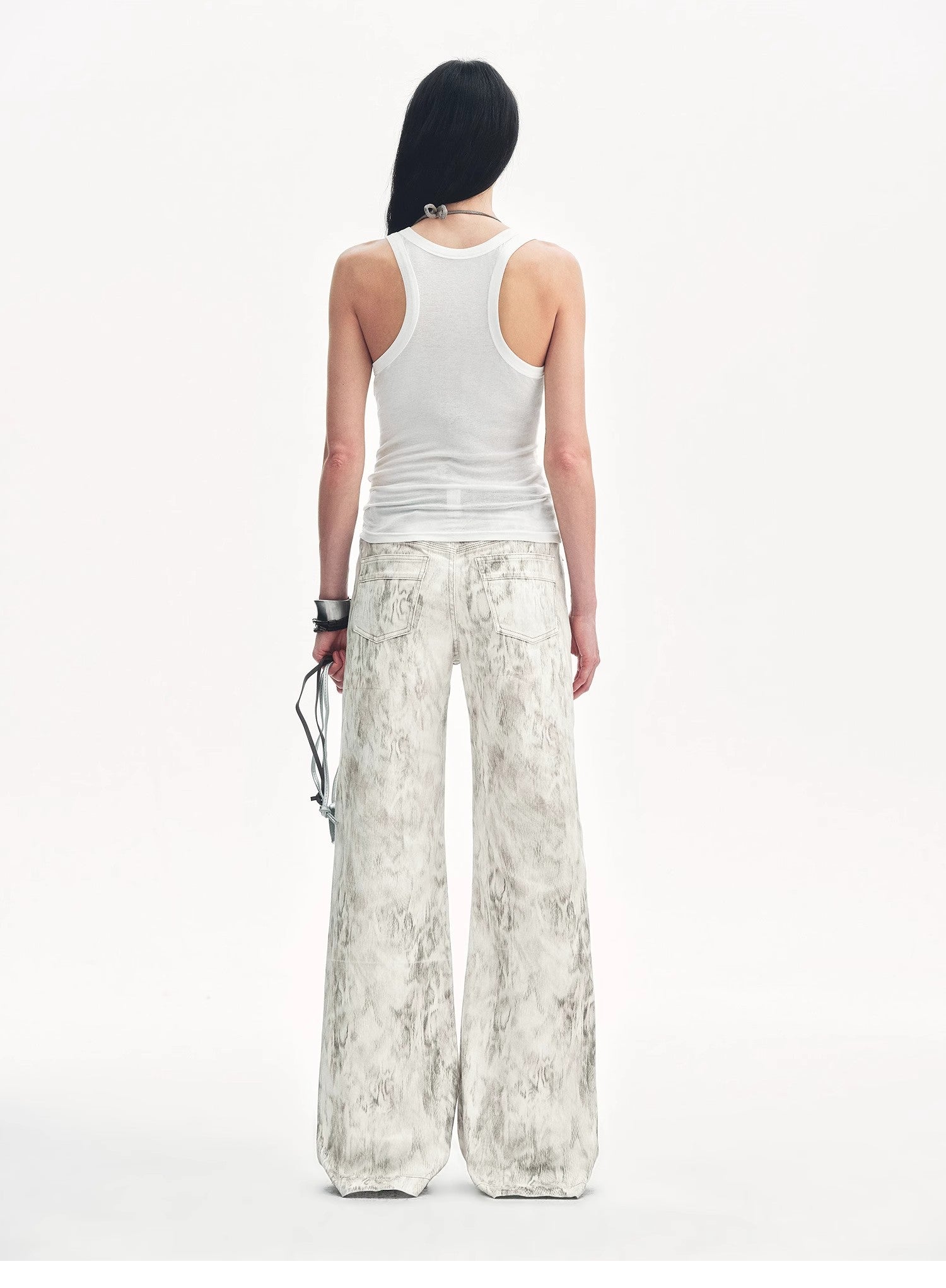 Person wearing a white tank top and patterned pants on a white background
