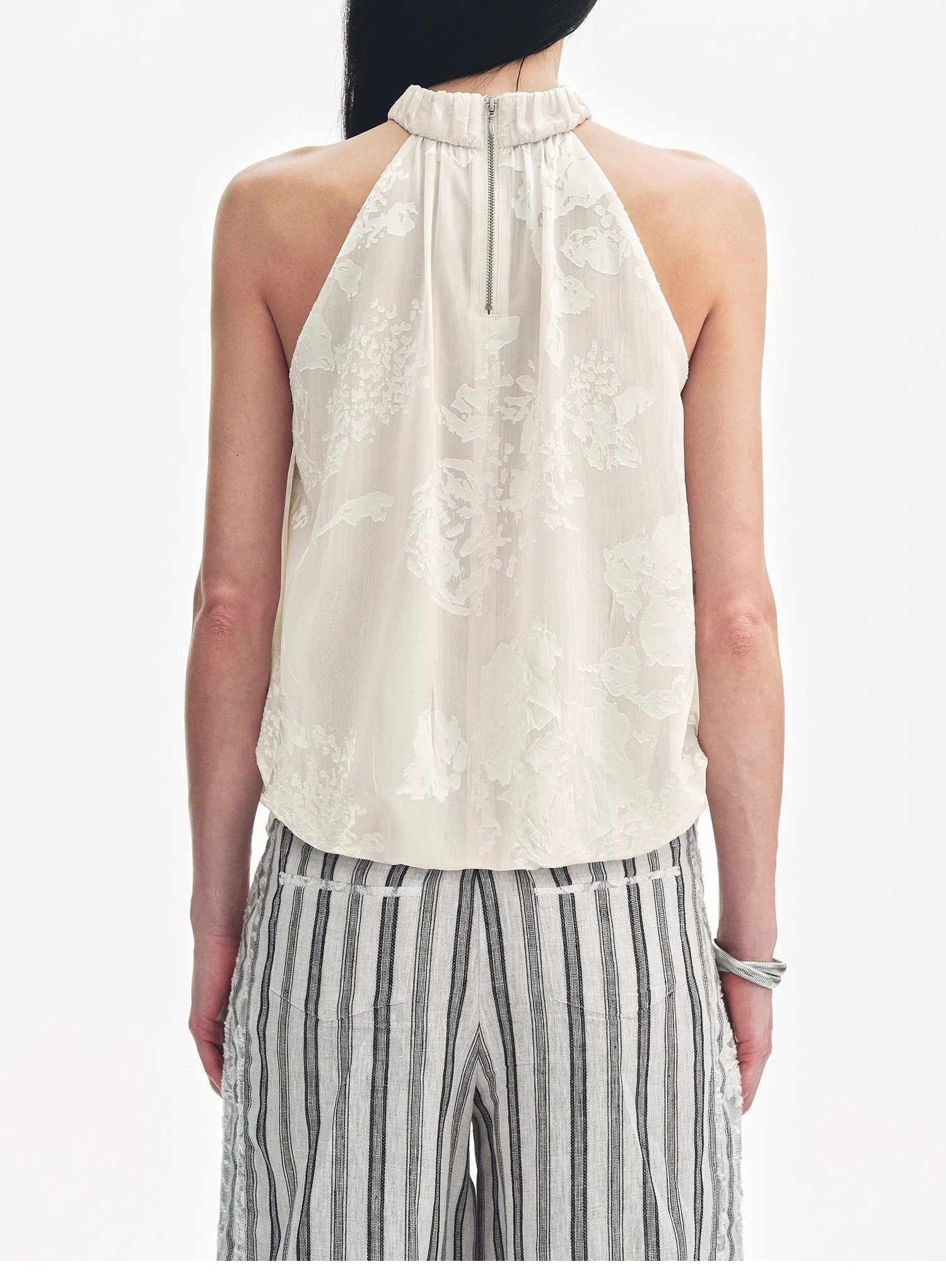 Woman wearing a white halter top and striped pants on a white background