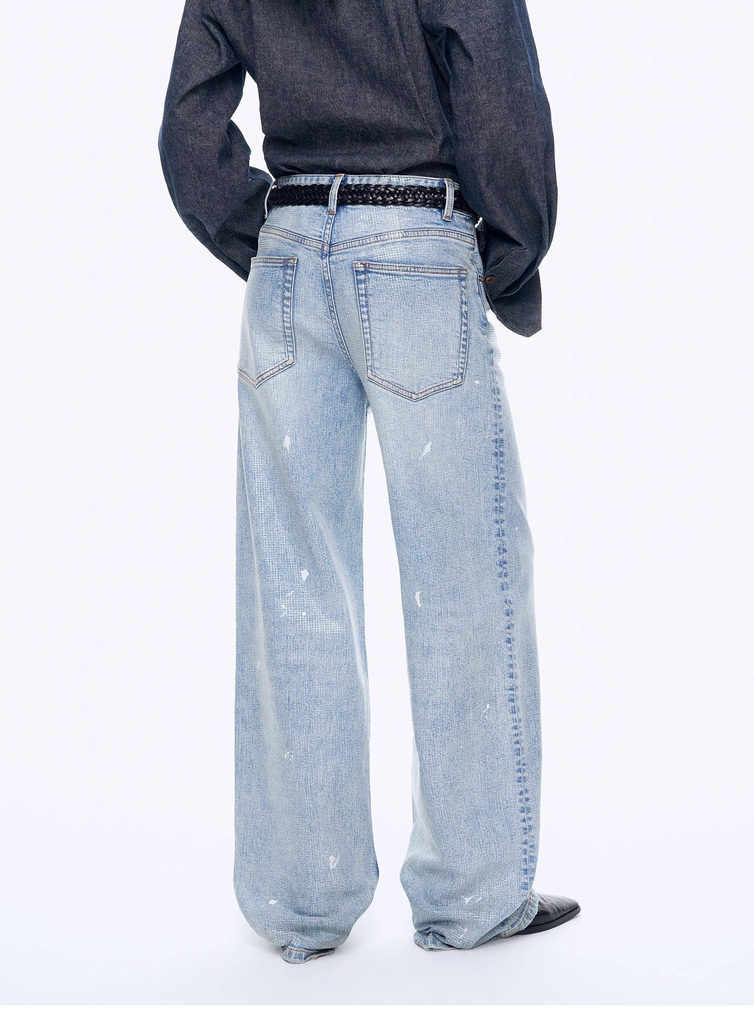 Person wearing light blue jeans and a dark shirt on a white background