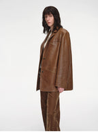 Person wearing a brown leather jacket and pants on a white background