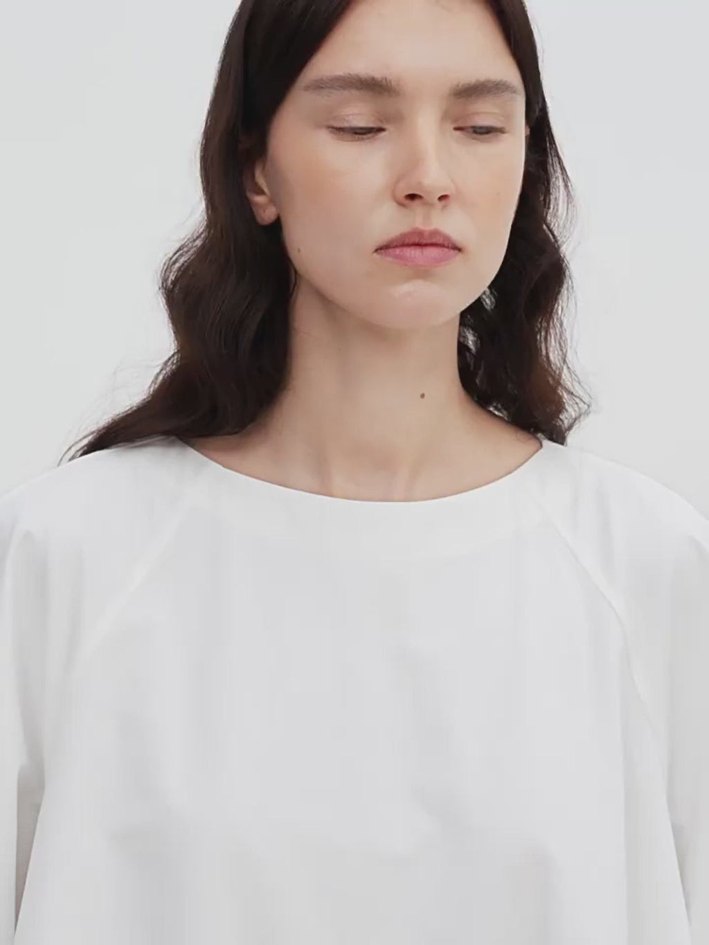 Woman wearing a plain white shirt against a light background