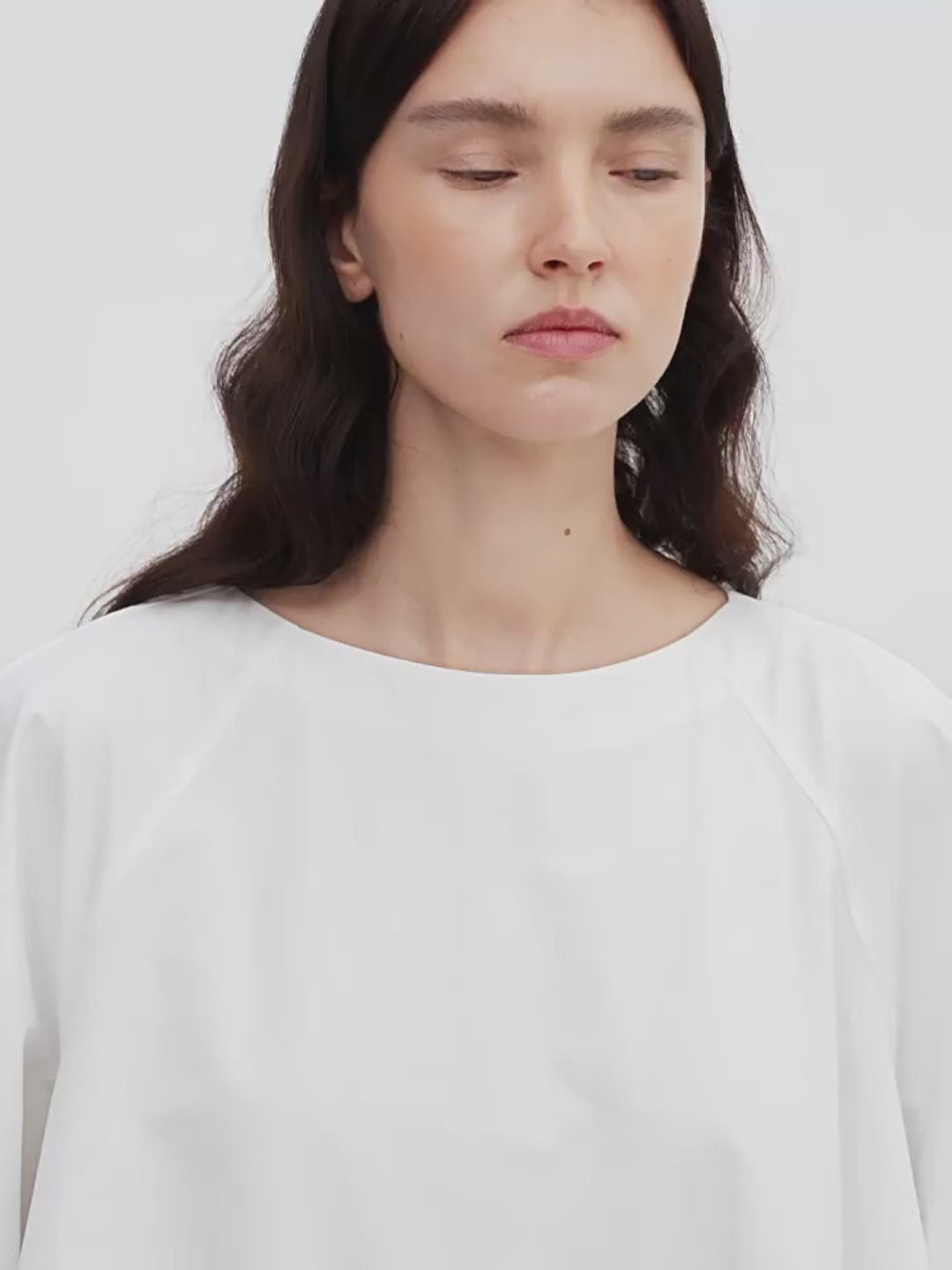Woman wearing a plain white shirt against a light background