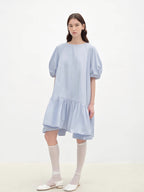 Woman wearing a light blue dress with puffed sleeves on a white background