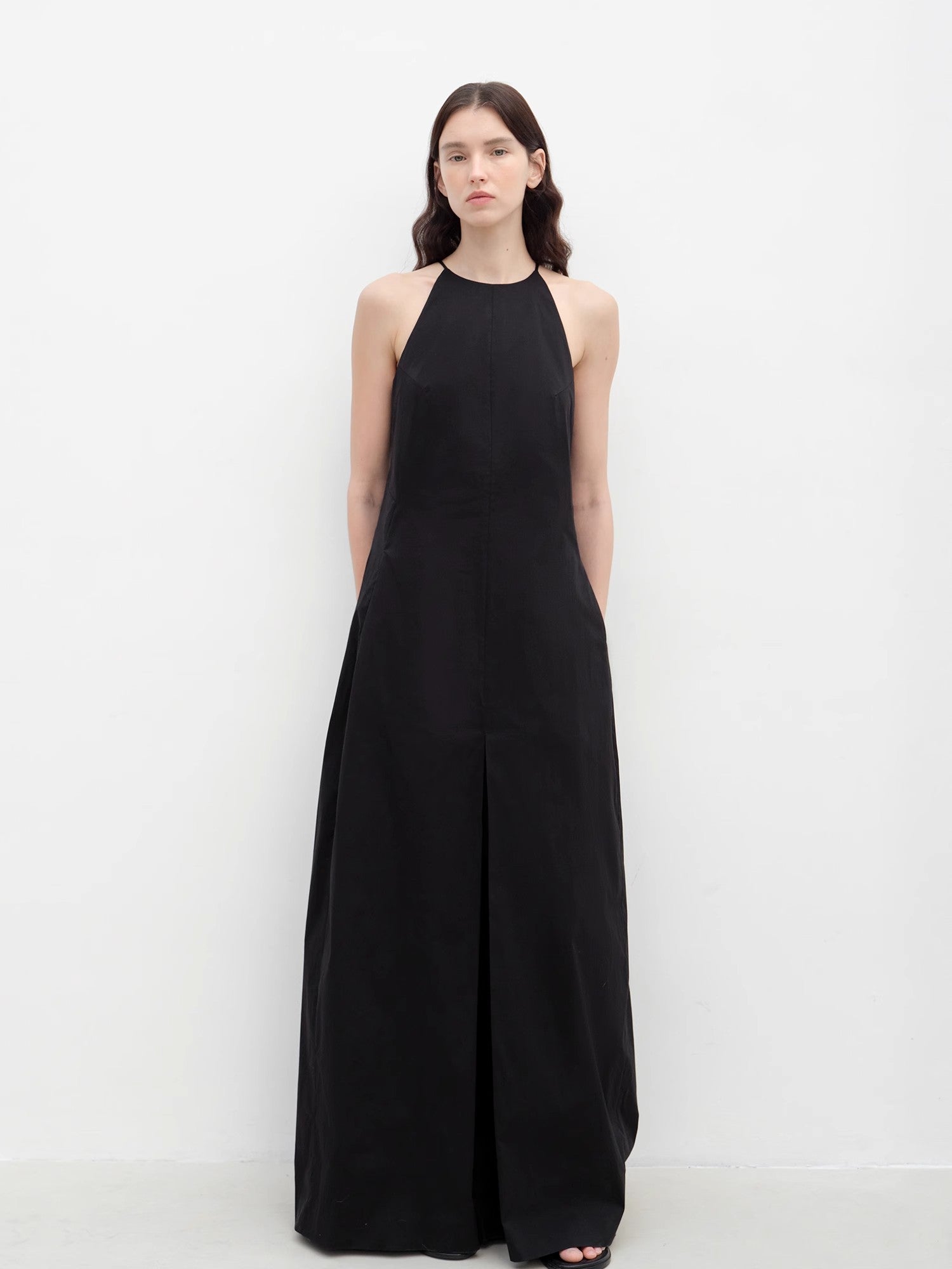 Woman wearing a black halter neck dress against a white background
