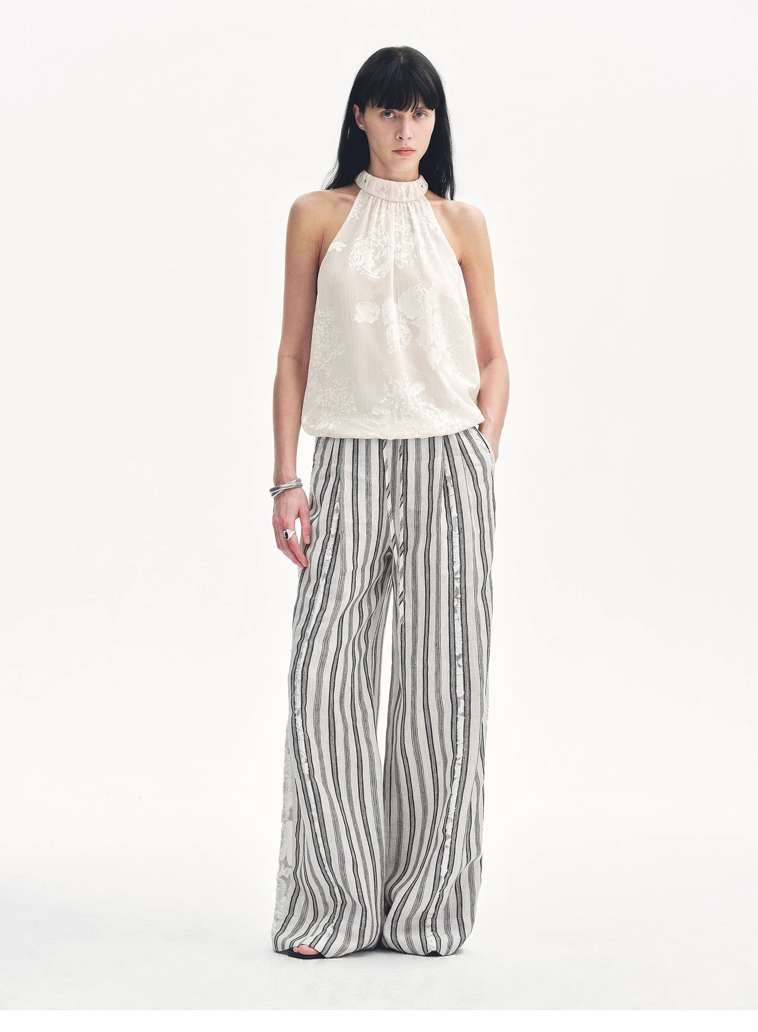 Woman wearing a white halter top and striped pants on a white background