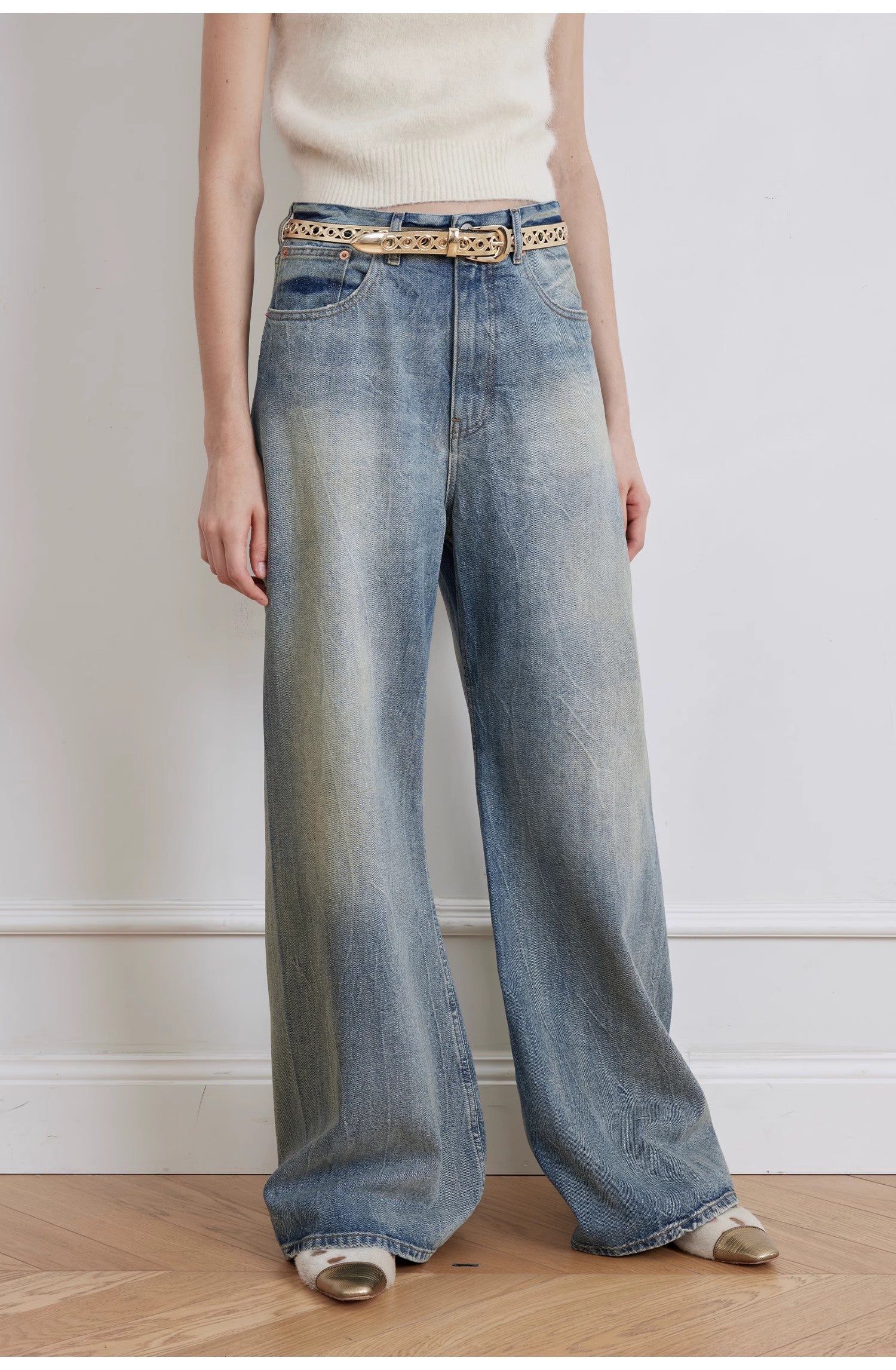 Person wearing wide-leg jeans with a belt against a plain background