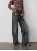 Person wearing a patterned sweater and blue jeans with leopard print shoes on a plain background