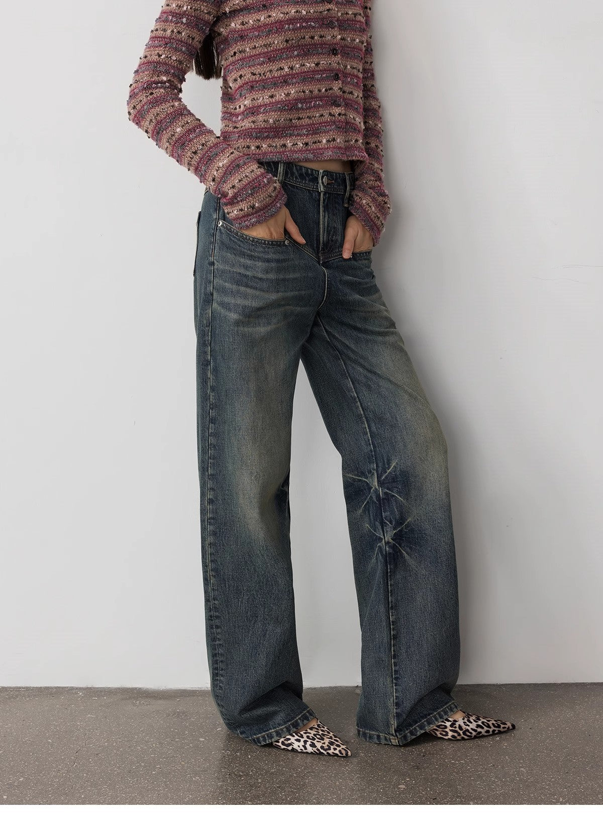Person wearing a patterned sweater and blue jeans with leopard print shoes on a plain background