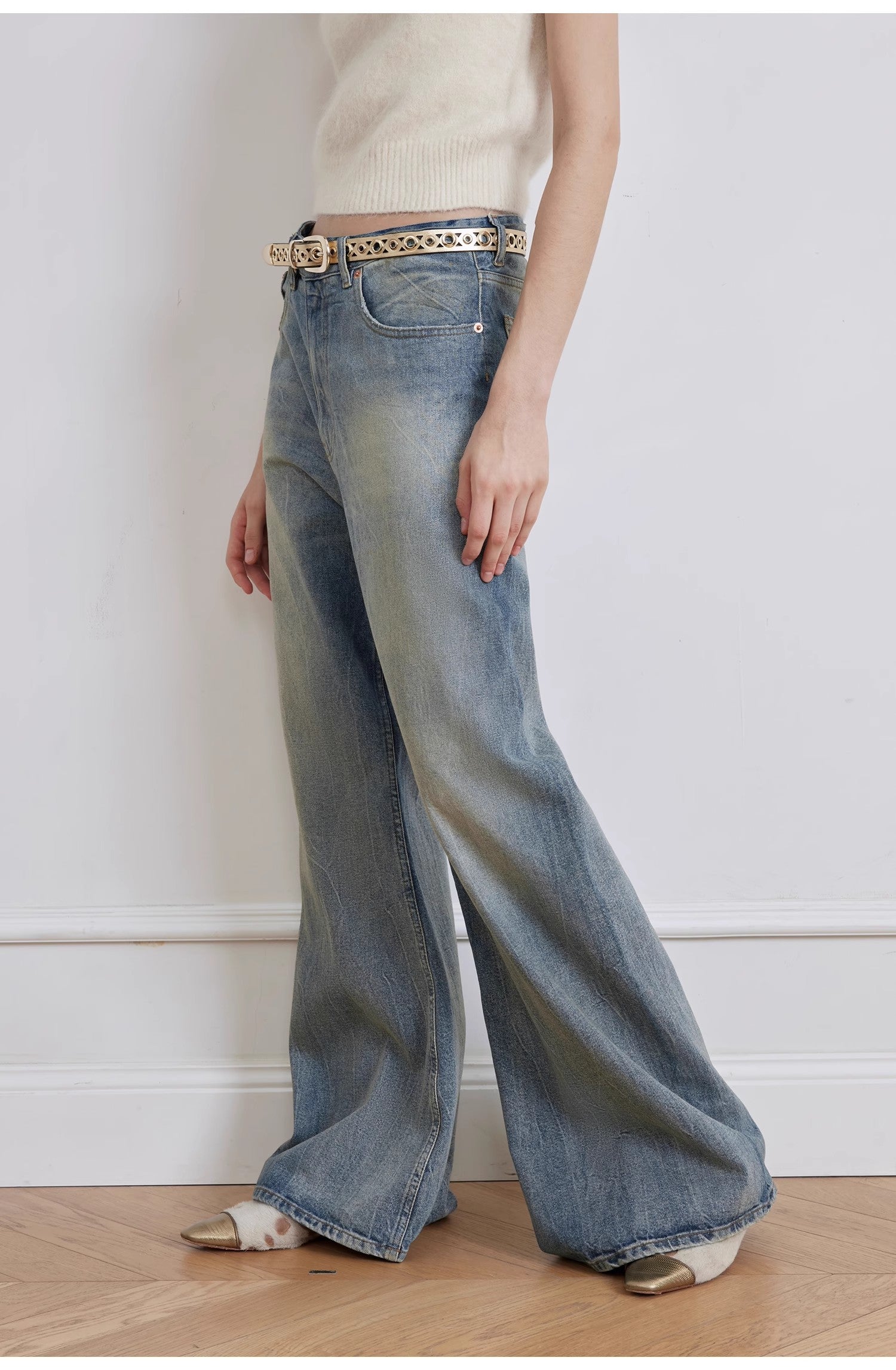 Person wearing wide-leg jeans with a white top and gold belt.