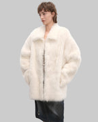 Woman wearing a white fur coat against a plain background