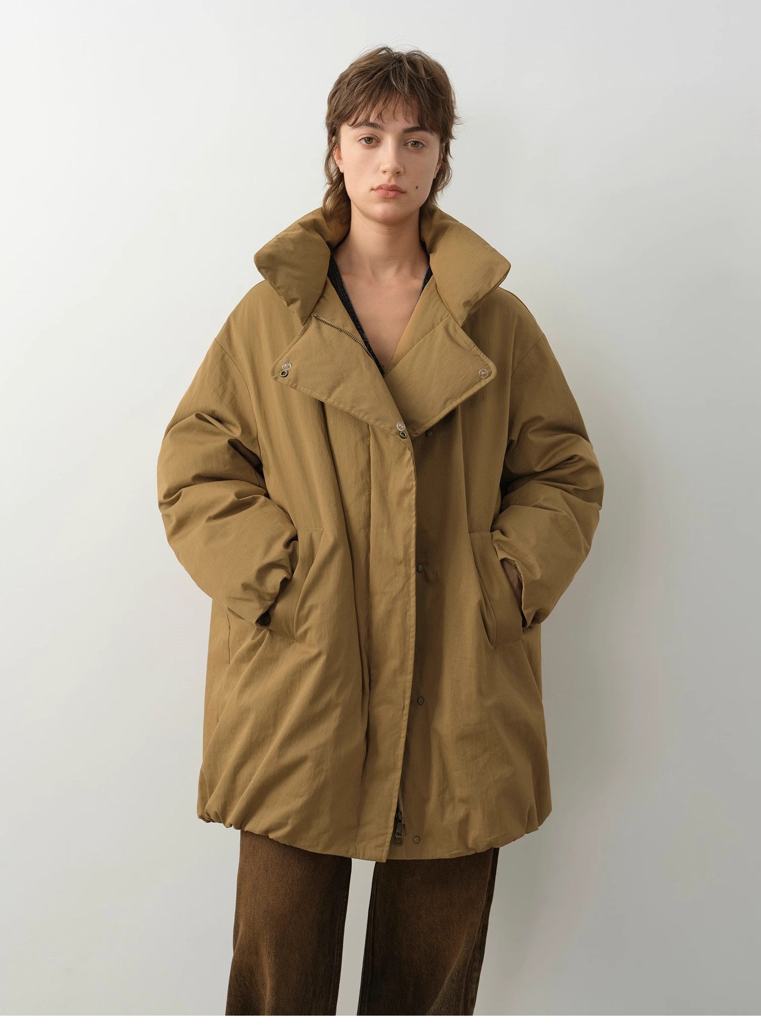 Person wearing a brown coat against a white background