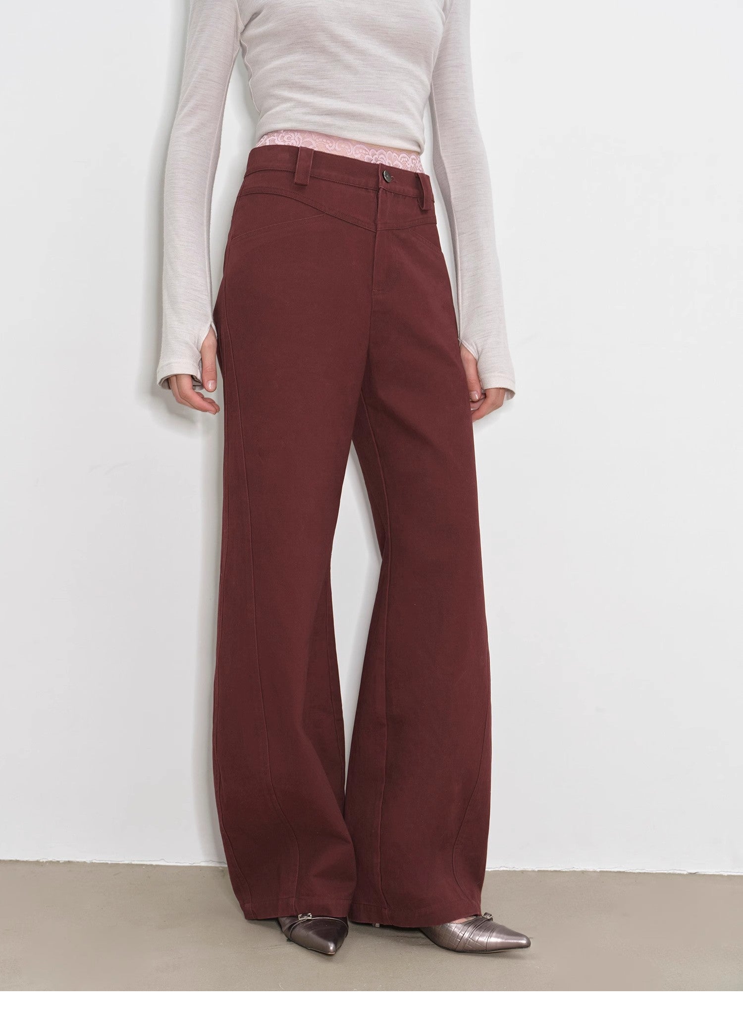 Person wearing maroon flared pants with a plain white background