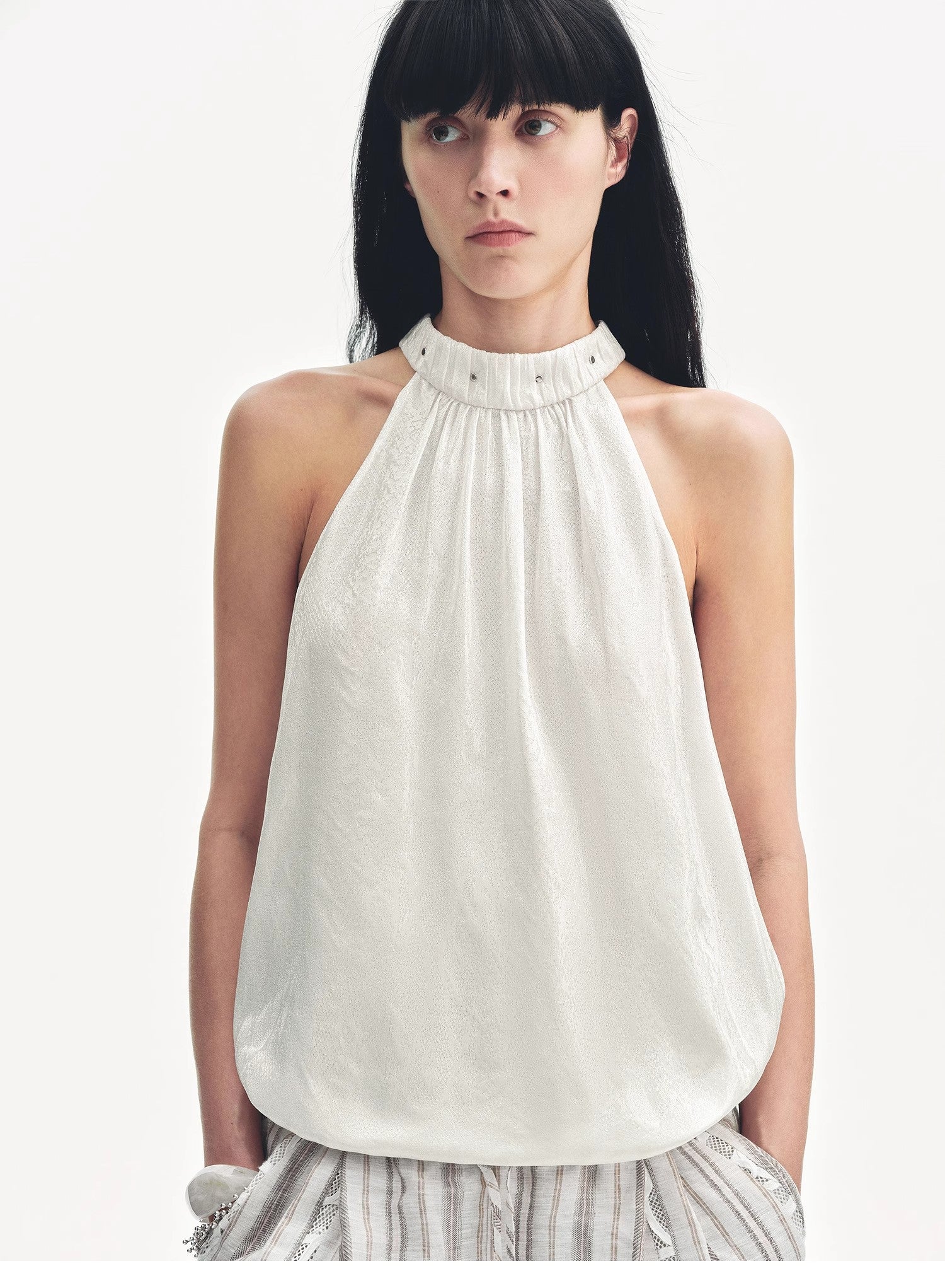Woman wearing a white halter top against a plain background