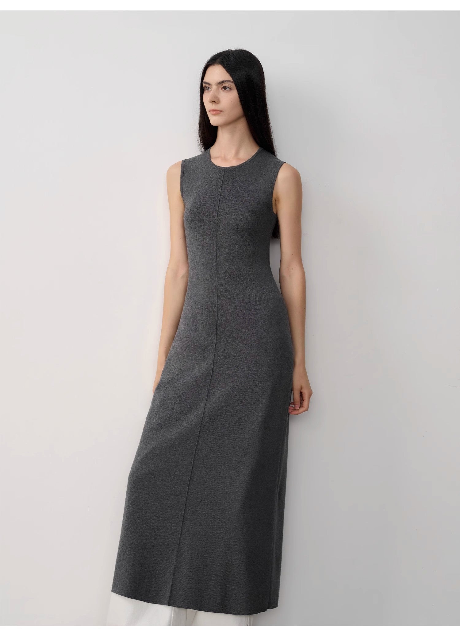 Woman wearing a gray sleeveless dress against a white background