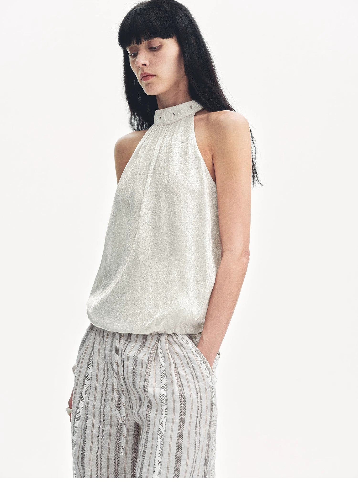 Woman wearing a white halter top and striped pants on a white background