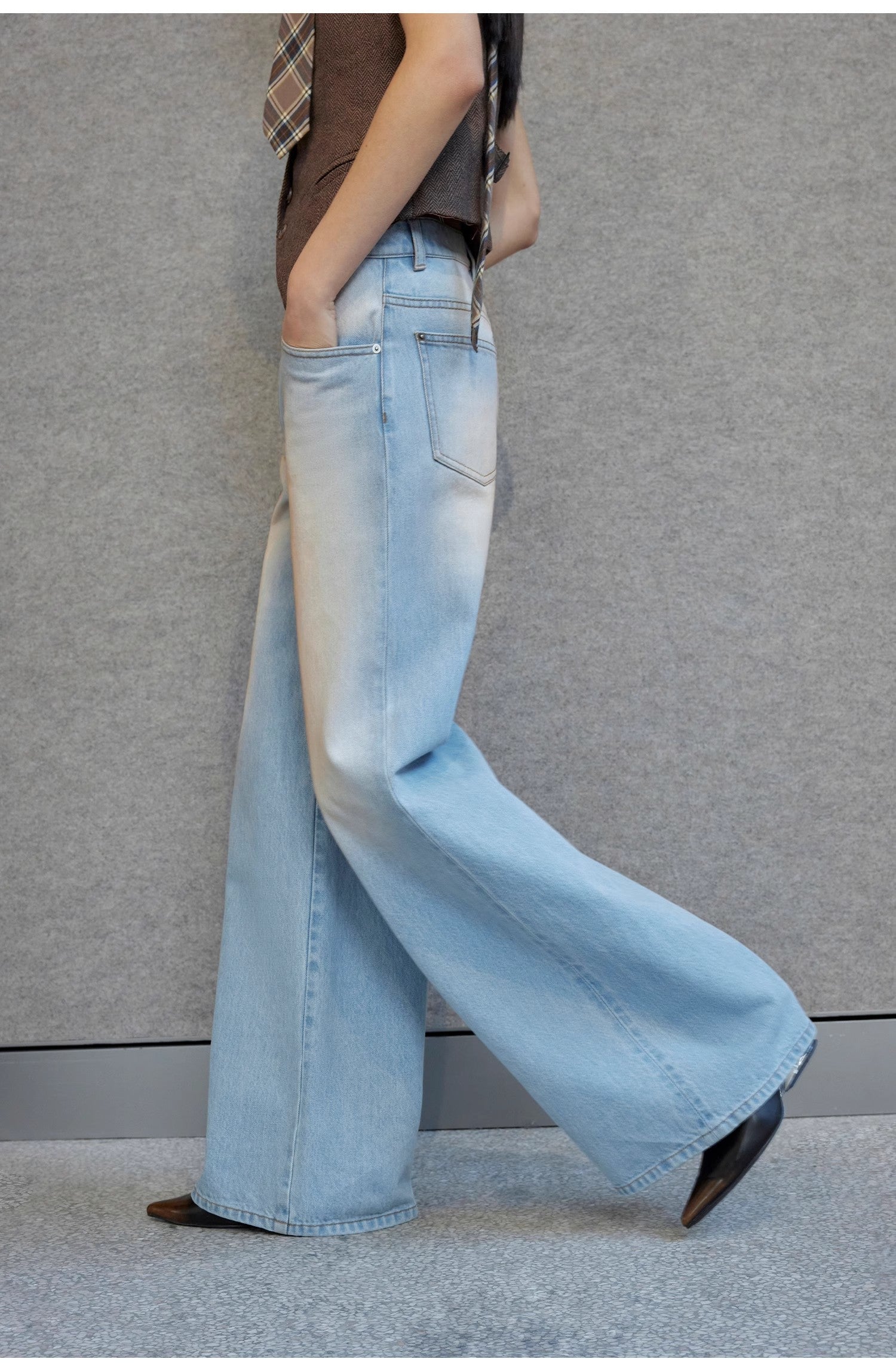 Light blue flared jeans worn by a person against a gray background