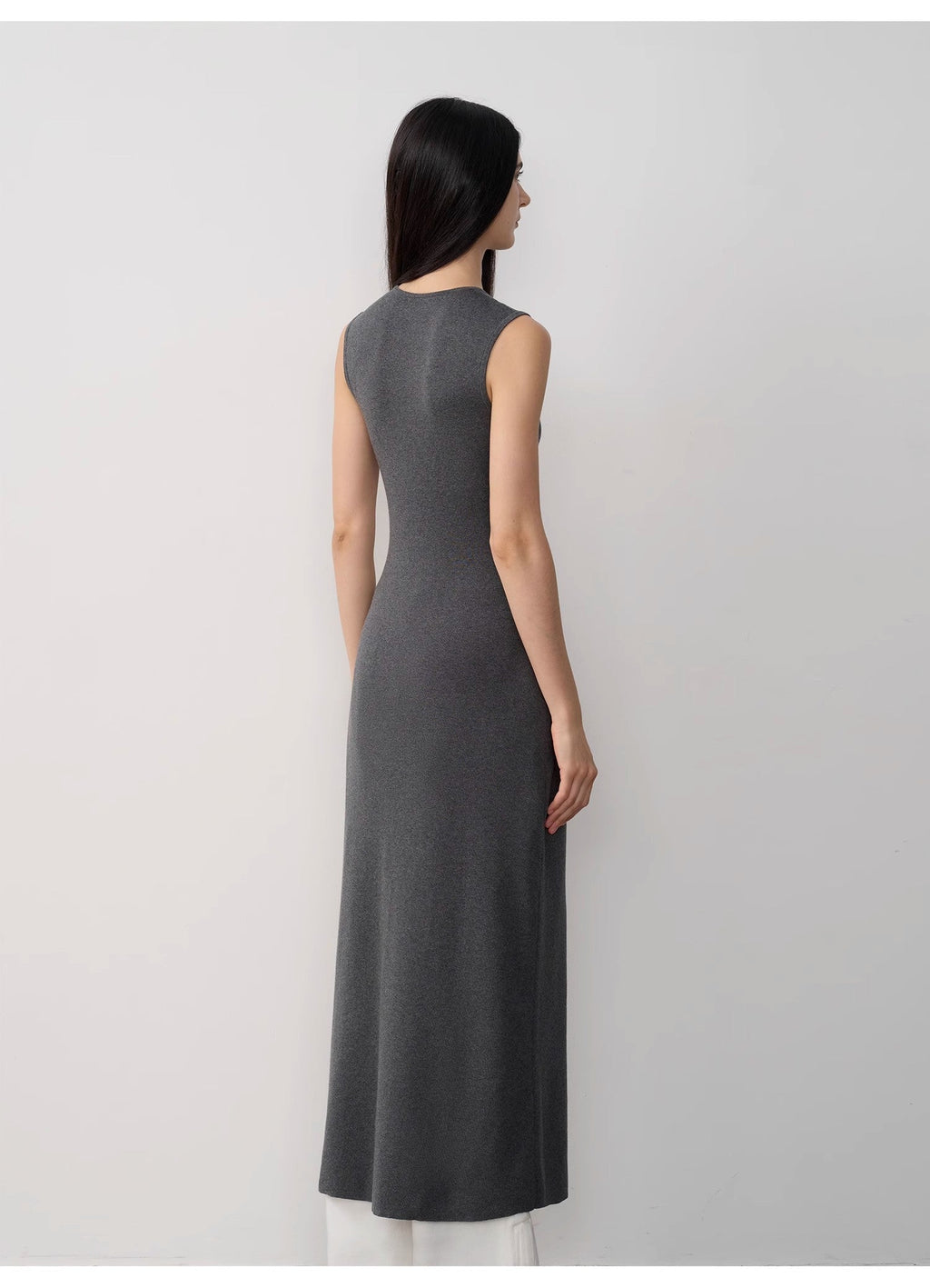 Woman wearing a gray sleeveless dress against a white background