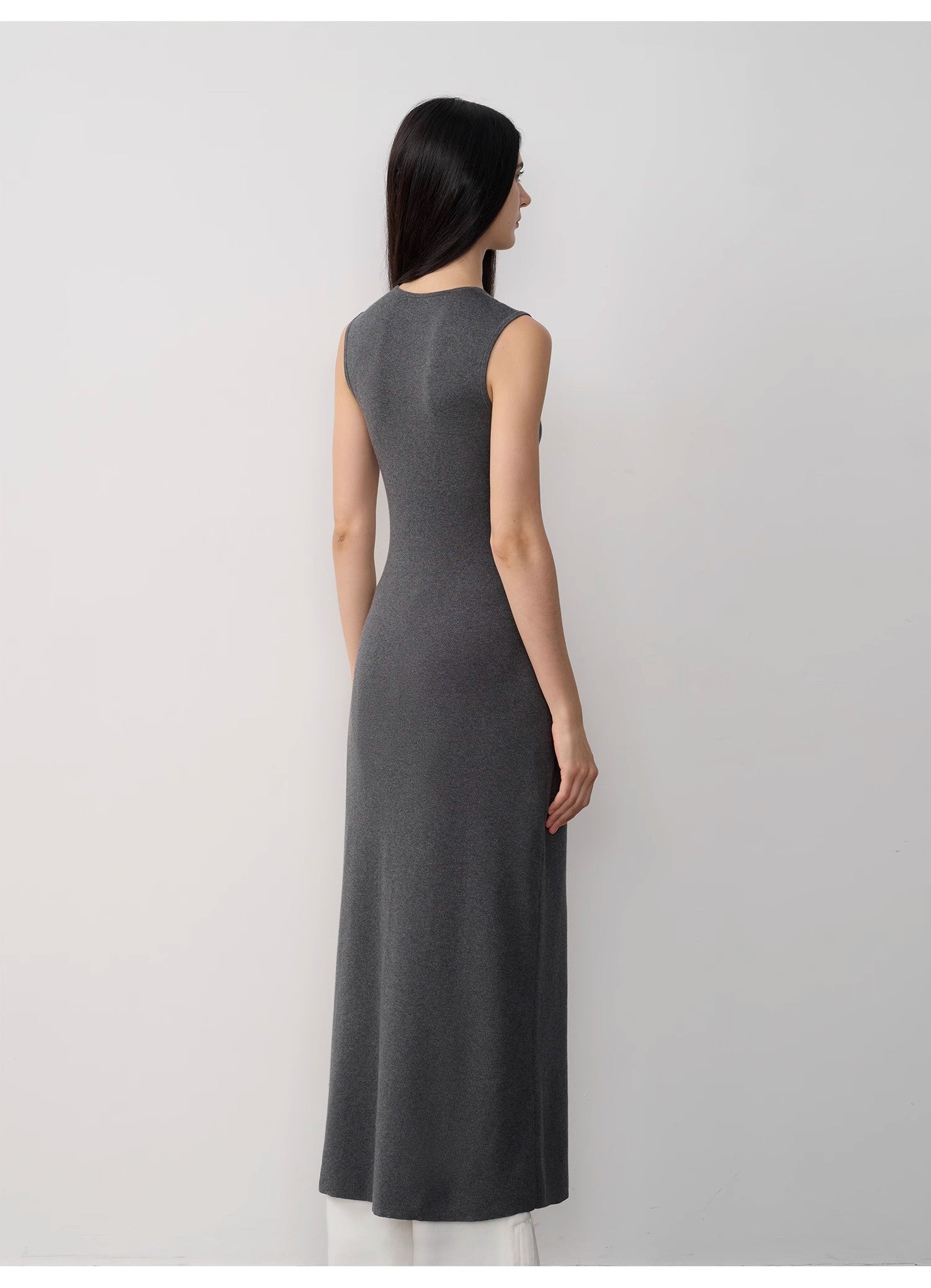 Woman wearing a gray sleeveless dress against a white background