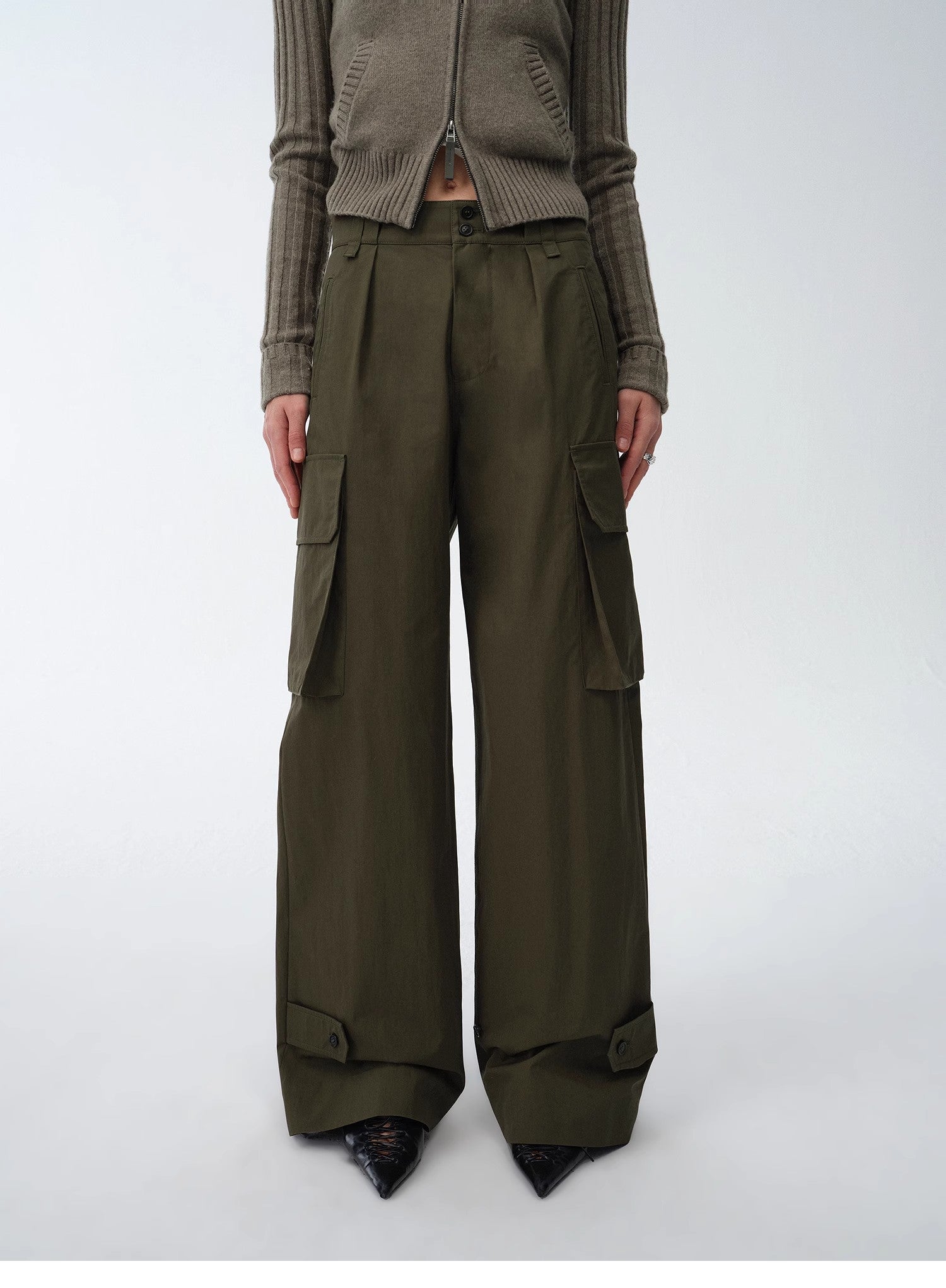 Person wearing olive green cargo pants and a matching cardigan on a white background