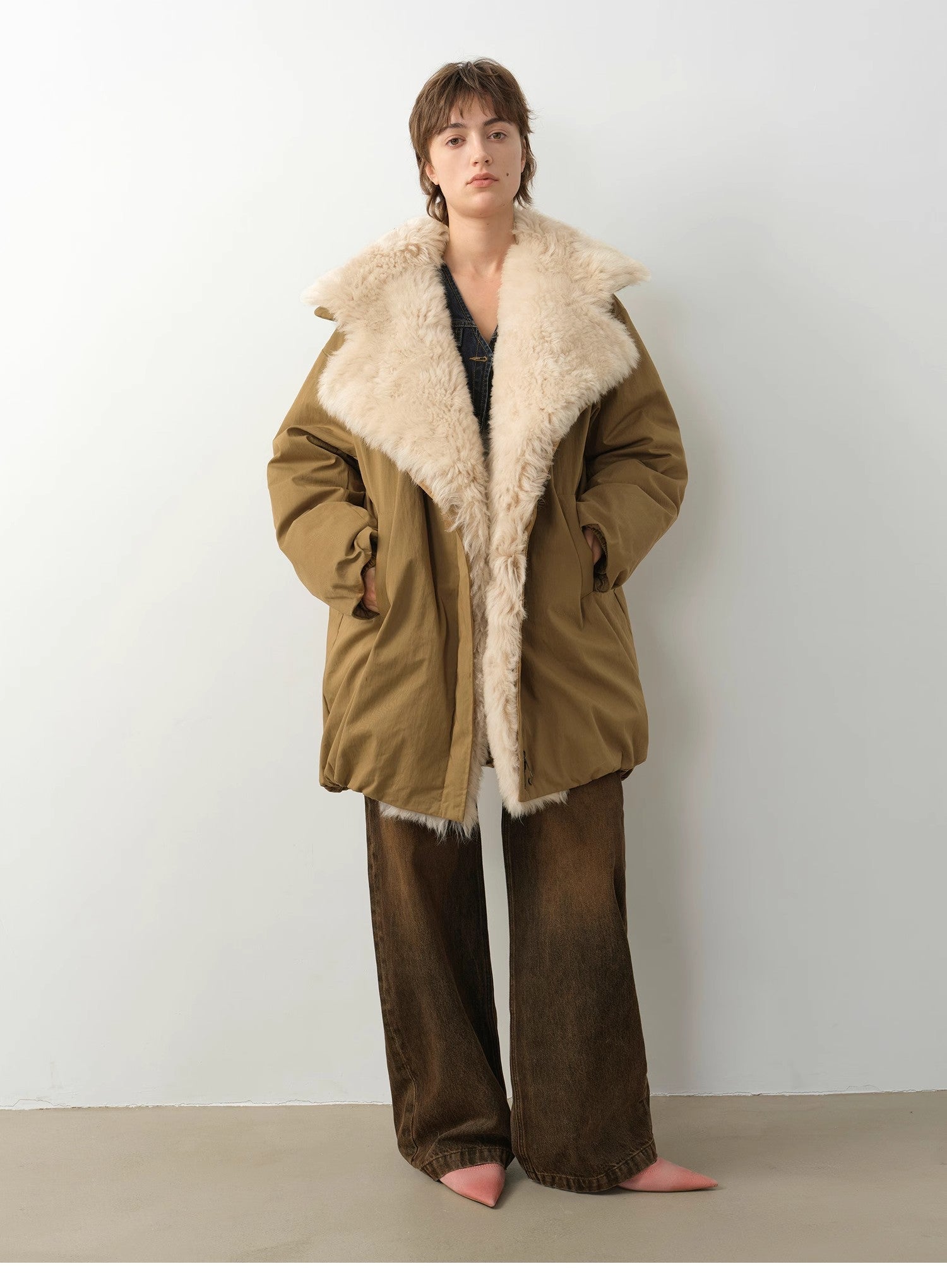 Person wearing a brown coat with a fur-lined hood against a white background