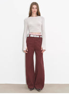 Model wearing a white long-sleeve top and maroon pants on a plain background