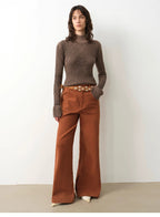 Woman wearing a brown ribbed sweater and rust-colored wide-leg pants against a white background