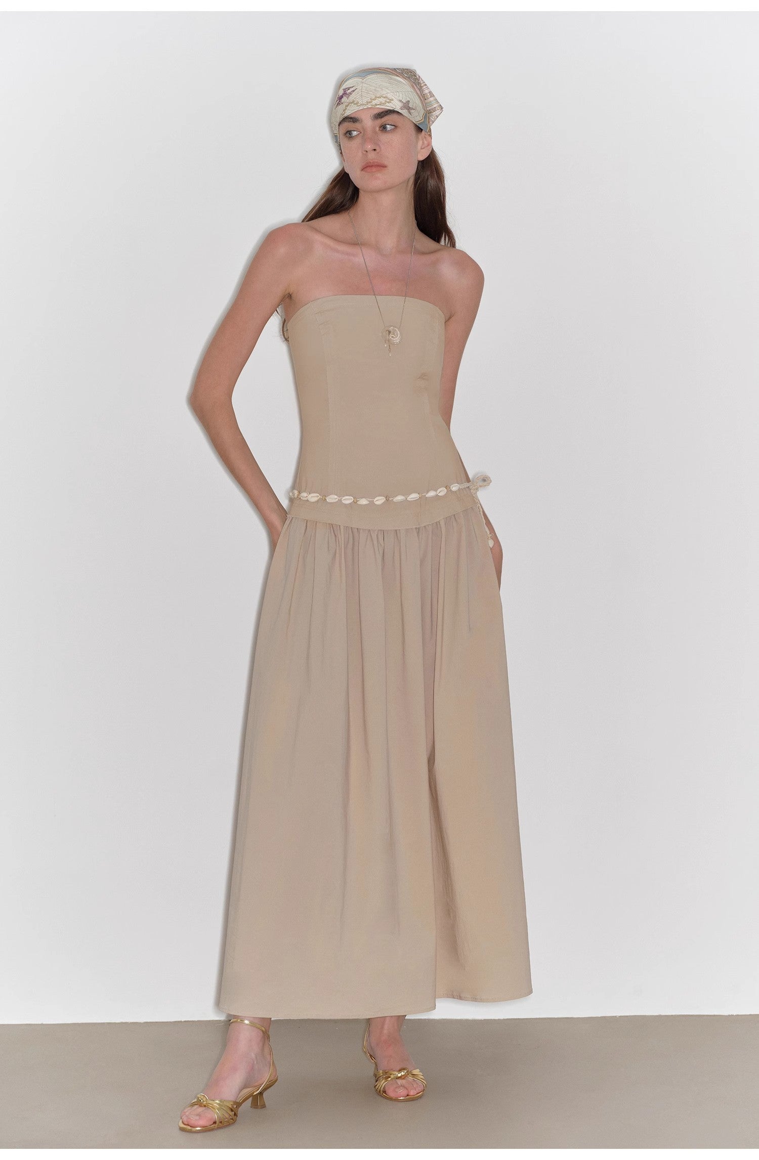 Woman wearing a beige strapless dress with a plain background