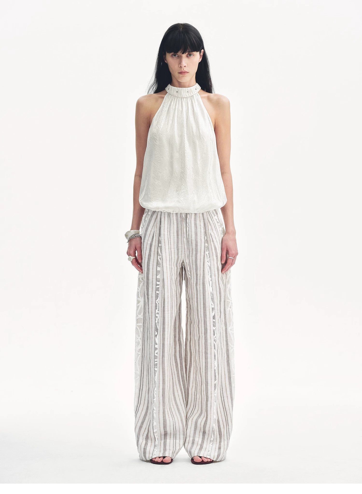 Woman wearing a white halter top and striped pants on a white background