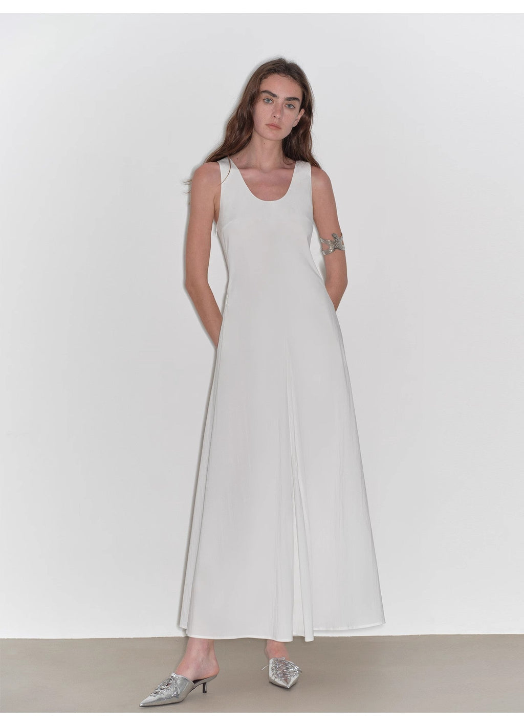 Woman wearing a white sleeveless dress against a plain background
