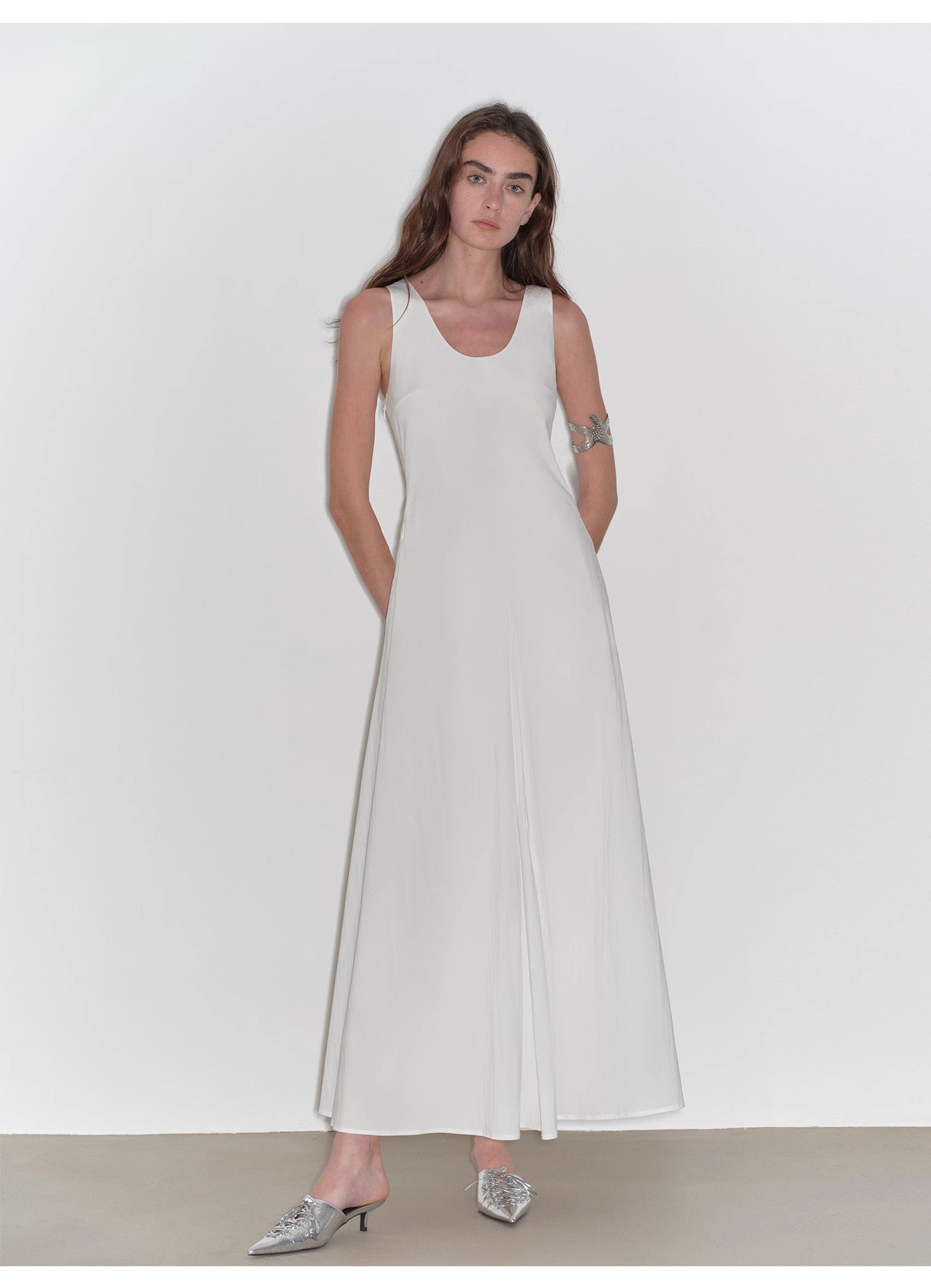 Woman wearing a white sleeveless dress against a plain background