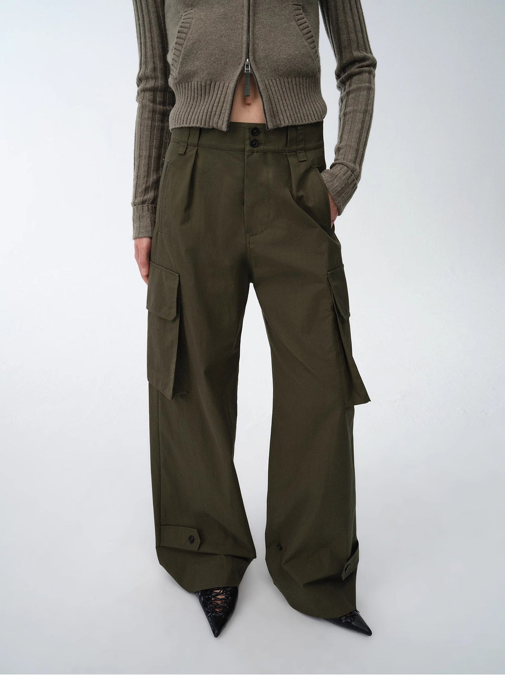 Person wearing a brown knitted cardigan and wide-leg cargo pants on a white background
