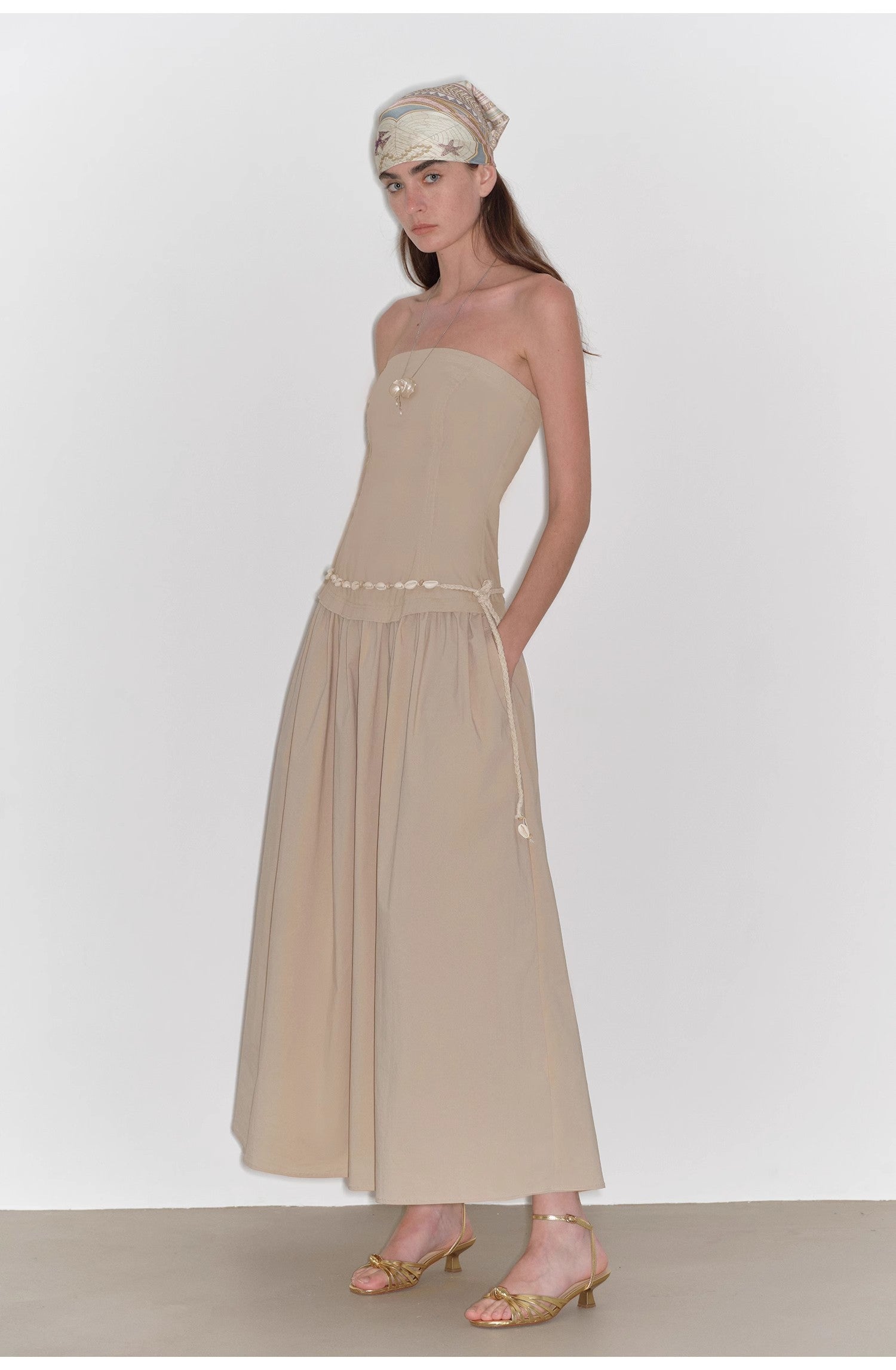 Woman wearing a beige strapless dress with a plain background