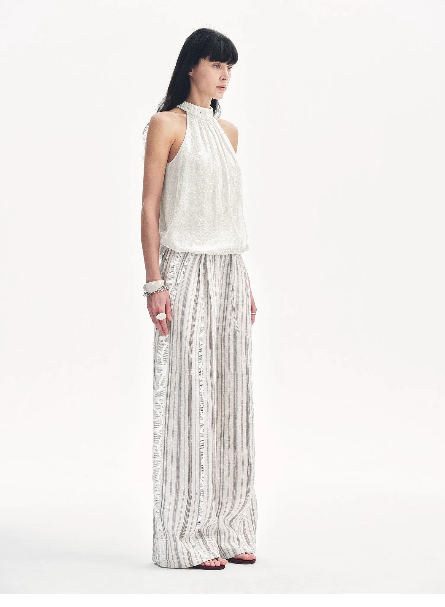 Woman wearing a white halter top and striped pants on a white background