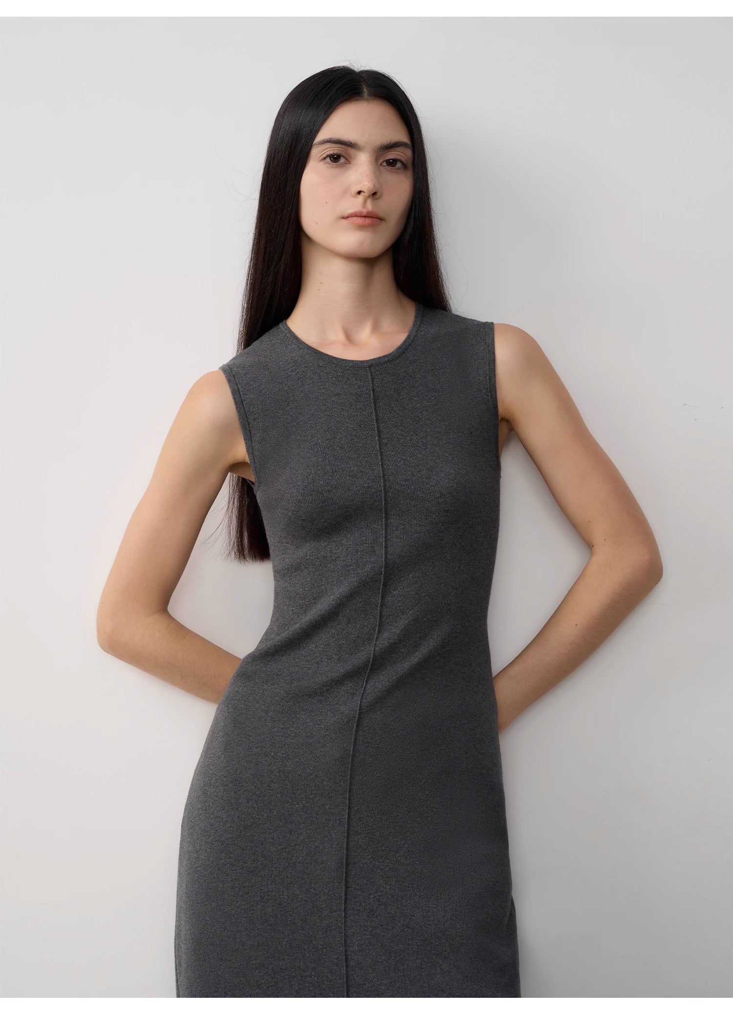 Woman wearing a gray sleeveless dress against a plain background