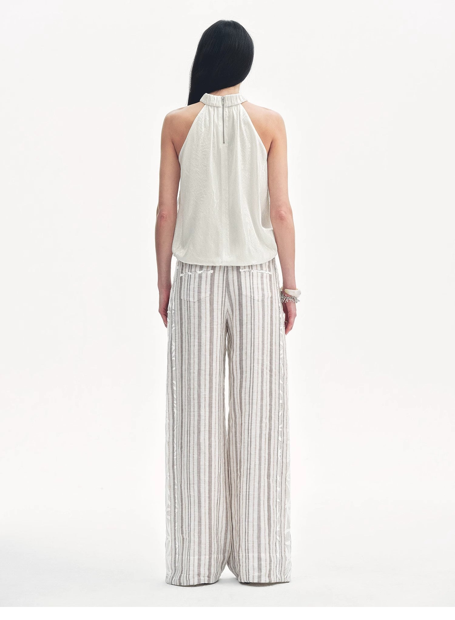 Woman wearing a white halter top and striped pants on a white background