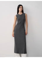 Woman wearing a gray sleeveless dress against a white background