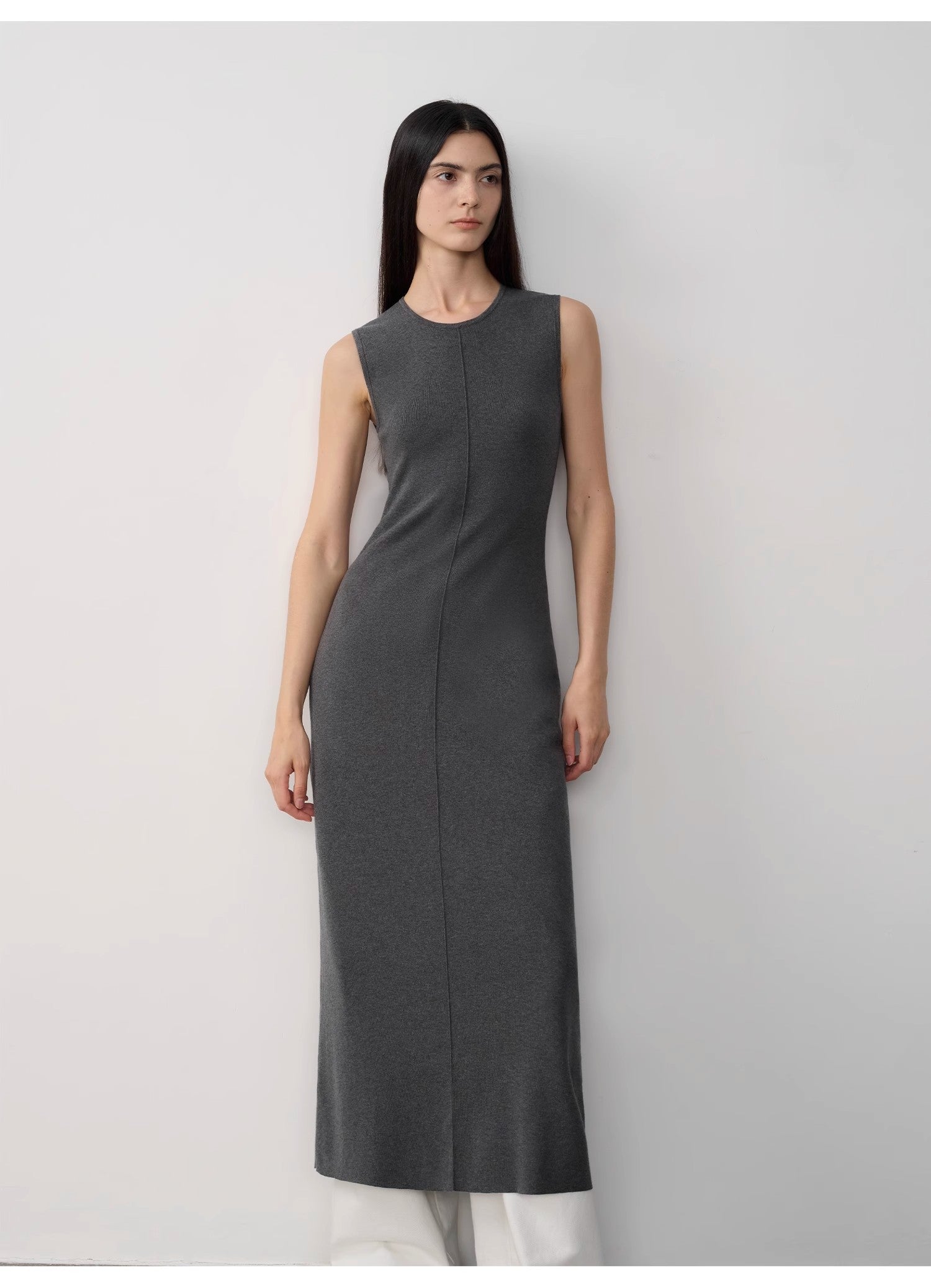 Woman wearing a gray sleeveless dress against a white background