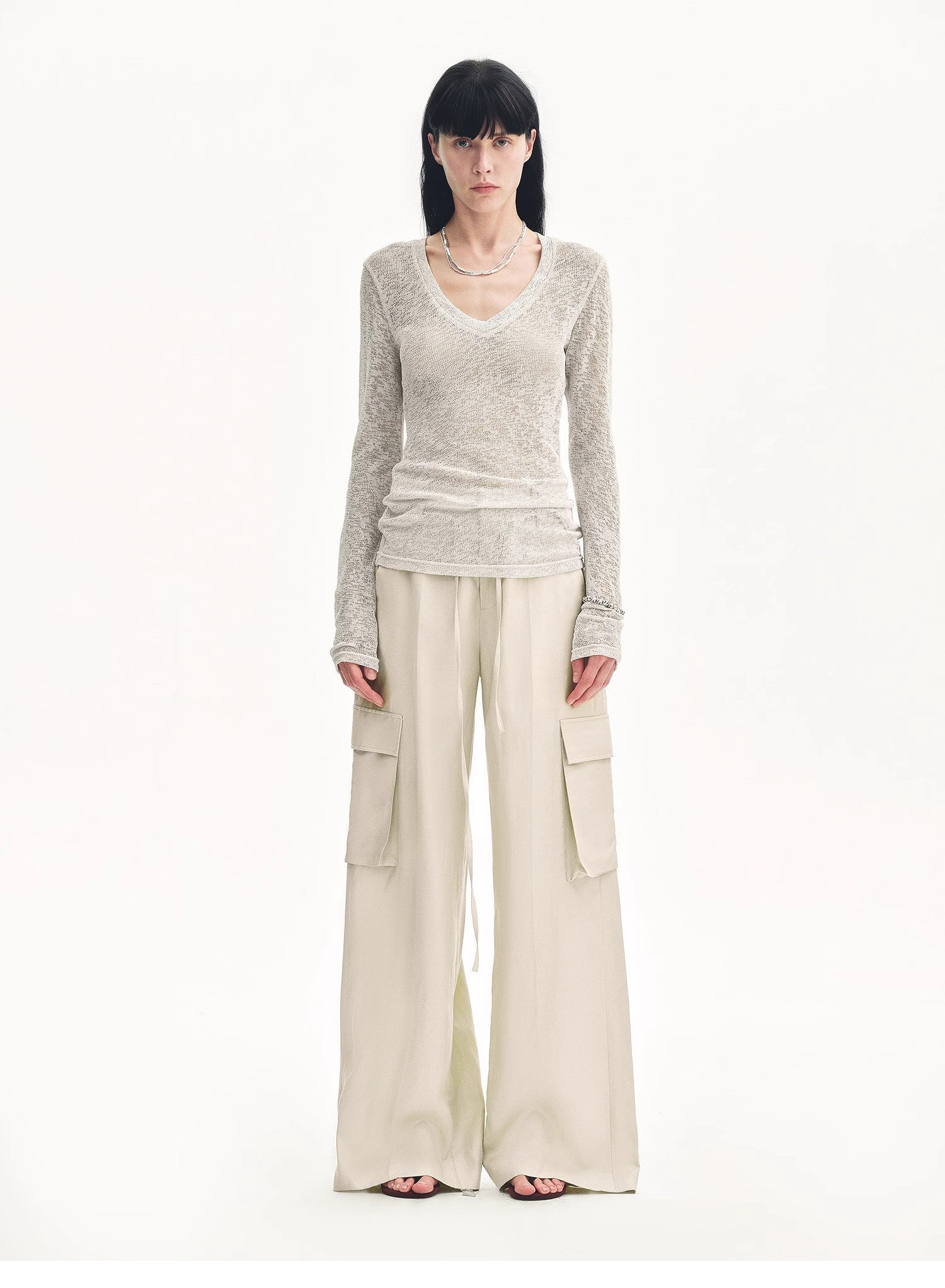Woman wearing a long-sleeve top and wide-leg pants on a white background